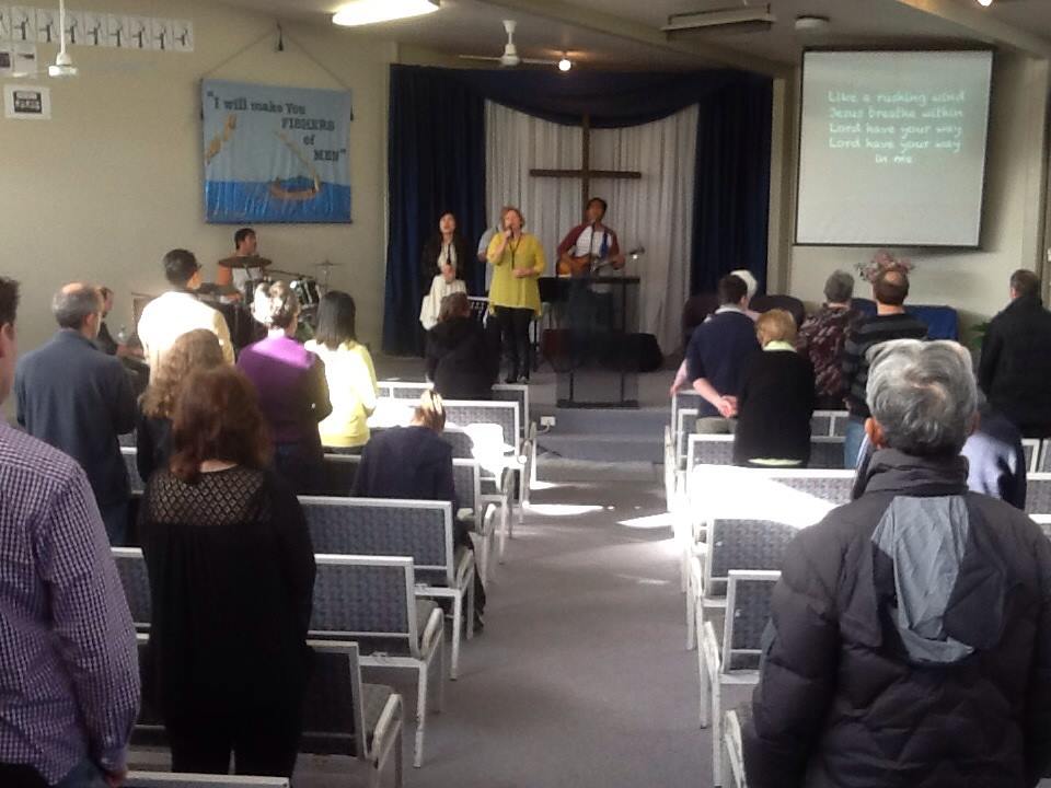 A man and two women singing during praise and worship in Glenfield Baptist Church's Sunday services.