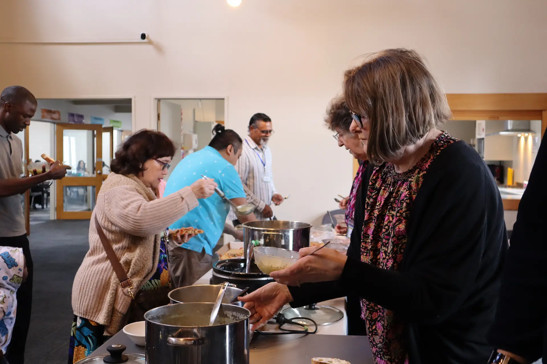 Various people conversing and getting food at a banquet table during Glenfield Baptist Church's shared lunch events.