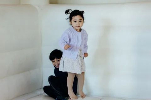 A young Filipino toddler jumping in a white bouncy castle.