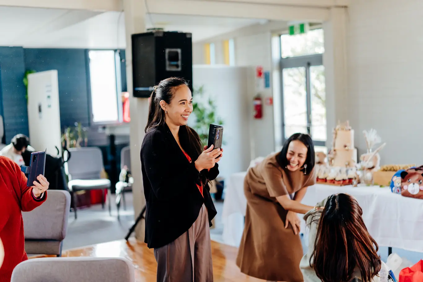 A Filipino woman recording on her phone smiling as she watches the stage.